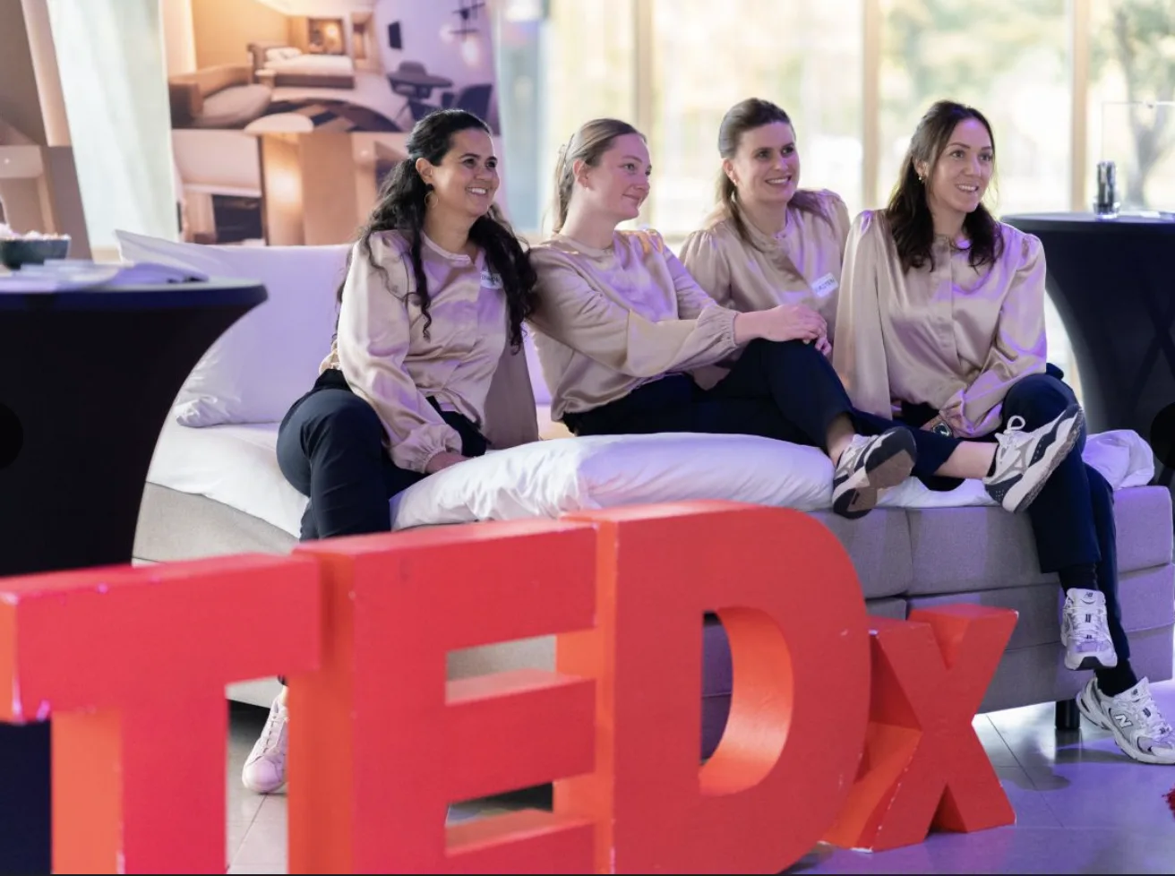 Team op een bed met de rode TEDx-letters op de voorgrond