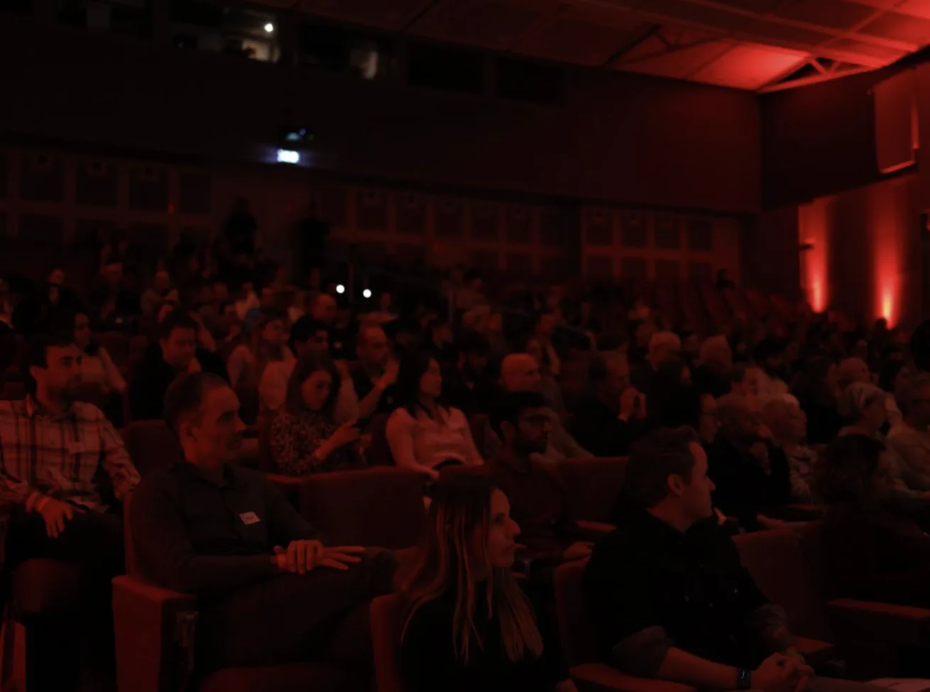 Publiek in rood licht tijdens een talk